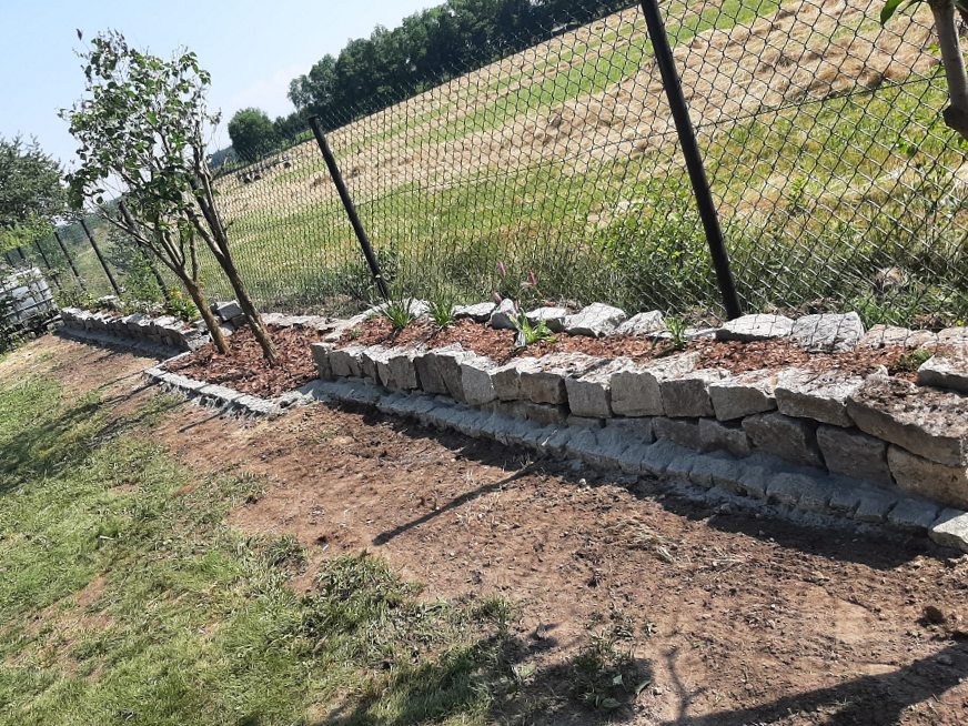 Zbliżenie kamiennej rabaty z korą i nowymi nasadzeniami